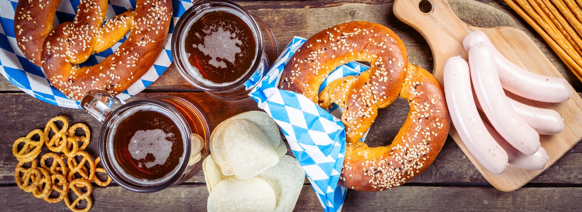 oktoberfest pretzels, beer, bratwurst, and napkins on table