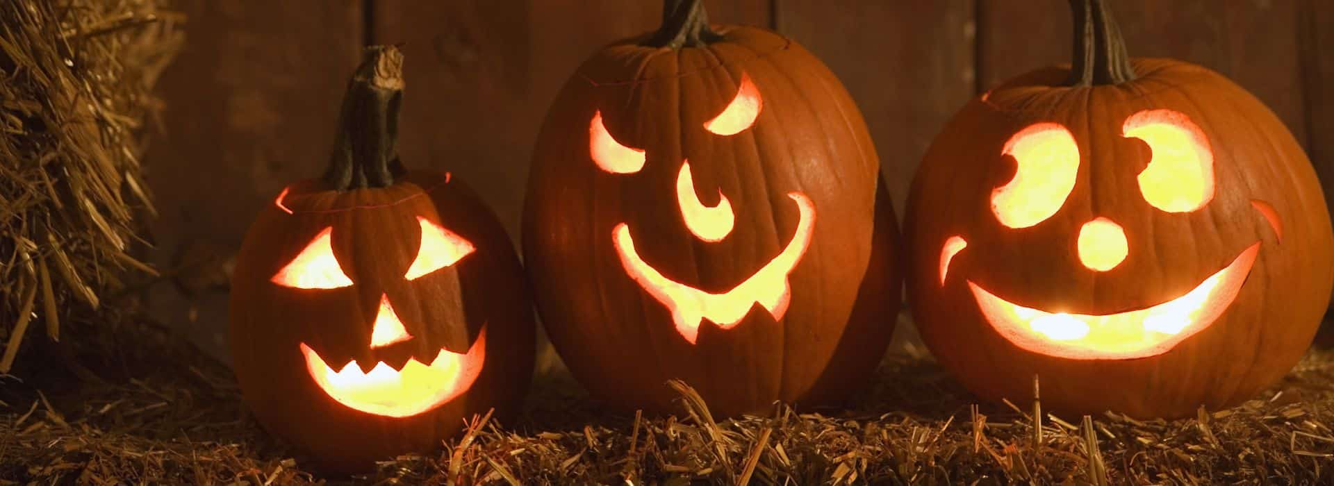 Three glowing jack o lanterns on haybale 