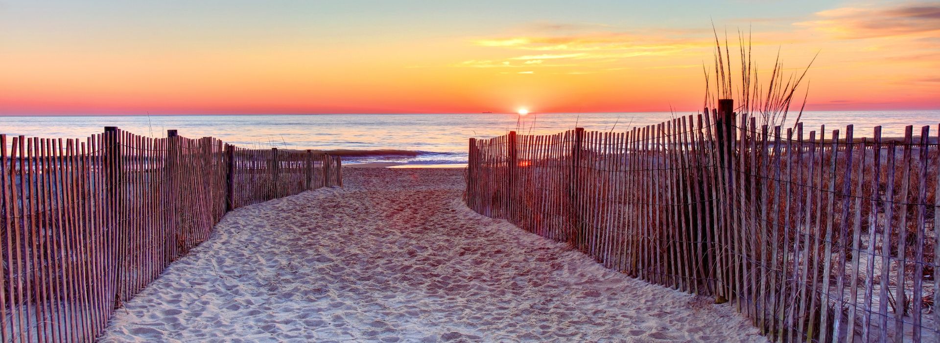 sunrise over rehoboth beach fenced sandy trail leading to water